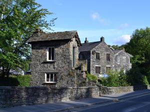 una vieja casa de piedra al lado de una carretera en Glenmore Cottage, en Ambleside