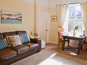 a living room with a leather couch and a table at Grosvenor Cottage in Alnmouth