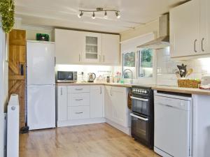 a kitchen with white appliances and white cabinets at The Summer House in Easthope