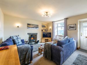 a living room with two blue couches and a fireplace at Carries Gate in Coniston