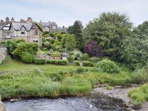 a house with a river in front of it at Quince Cottage - 25625 in Corbridge