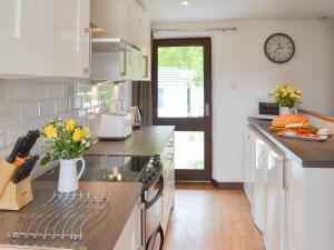 a kitchen with white cabinets and a counter with flowers at Sunset in Cheriton Bishop