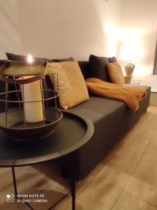 um sofá preto com almofadas e uma vela na mesa em logement Mezzanine salon indépendant em Mézières-sur-Seine