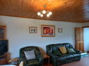 two leather chairs in a living room with a ceiling at Maggie's House in Glenties
