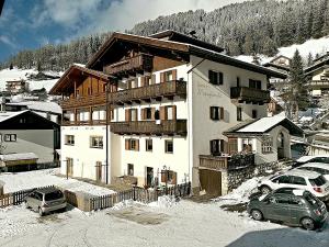 a large white building with cars parked in the snow at Garni Margherita in Corvara in Badia
