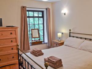 a bedroom with a bed with a dresser and a window at Wood Cottage in Whaley Bridge