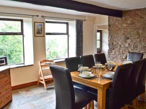 a dining room with a table and chairs and windows at Wood Cottage in Whaley Bridge