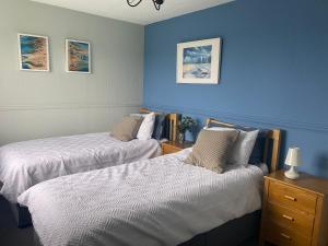 two beds in a room with blue walls at Ploughmans Cottage, St Florence, Tenby in Tenby