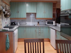 uma cozinha com armários verdes, uma mesa e uma cadeira em Scobach Lodge em Turriff