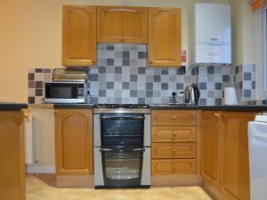 een keuken met houten kasten en een fornuis met oven bij High Fellside in Ambleside