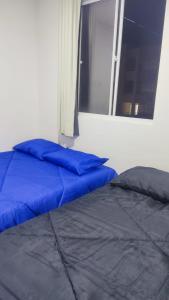 a bed with blue pillows in a room with a window at Mirantes caminho do mar in Parnamirim