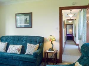 a living room with a blue couch and a lamp at Steep Holm in Kington