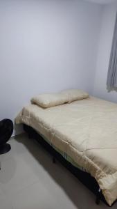 a bed in a room with a white wall at Mirantes caminho do mar in Parnamirim