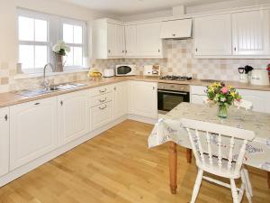 a kitchen with white cabinets and a table with flowers on it at Arden Cottage in Twynholm