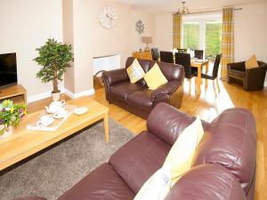 a living room with a leather couch and a table at Arden Cottage in Twynholm