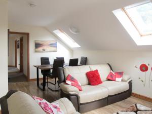a living room with a white couch and a table at Ysgubor Uchaf - 29517 in Fairbourne
