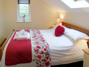 a bedroom with a bed with white sheets and red pillows at Ysgubor Uchaf - 29517 in Fairbourne