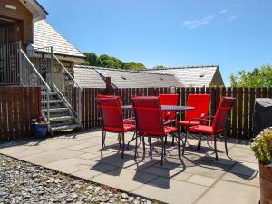 a group of red chairs and a table on a patio at Ysgubor Uchaf - 29517 in Fairbourne