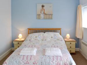 a bedroom with a bed with two night stands and two lamps at Sunset Cottage in Chickerell