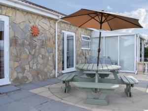 a picnic table with an umbrella on a patio at Sunset Cottage in Chickerell