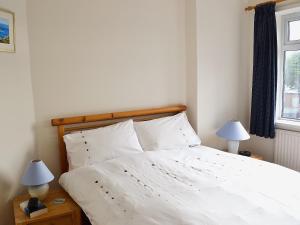 una camera da letto con un letto con lenzuola bianche e due lampade di Coastguard Cottage a Fleetwood