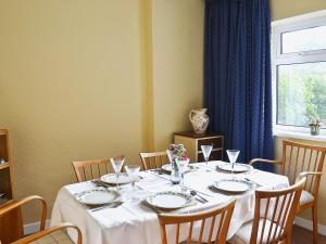 uma mesa de jantar com uma toalha de mesa branca e cadeiras em Coastguard Cottage em Fleetwood
