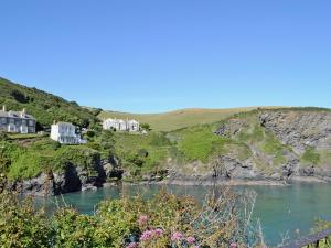 a group of houses on a cliff next to a body of water at Haven Cottage - 28269 in Port Isaac
