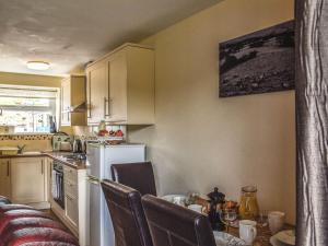 a kitchen with a table and a white refrigerator at Robin Cottage in Llandeilo