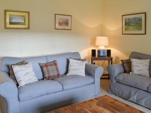 a living room with two blue couches and a lamp at Einich in Newtonmore