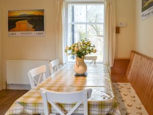 a dining room table with a vase of flowers on it at Einich in Newtonmore