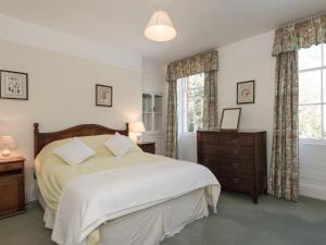 a bedroom with a bed and a dresser and windows at The Old Butlers House in Cley next the Sea