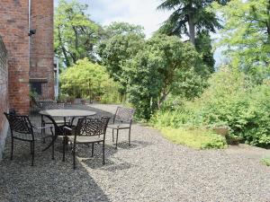 un patio con mesa y sillas en un jardín en Wisteria Loft-24773, en Tenbury