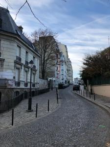 een geplaveide straat in een stad met gebouwen bij Rare appartement d'architecte en haut de Montmartre in Parijs