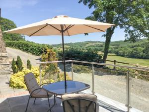 a table and chairs with an umbrella on a patio at Orchard Close -17380 in Kilkhampton