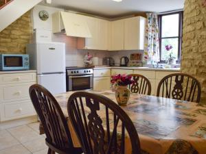 Chadlington的住宿－派克特帕斯小屋，厨房配有桌椅和冰箱。