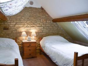 two twin beds in a room with a brick wall at Picket Piece Cottage in Chadlington