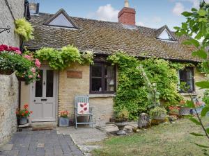 Cabaña con puerta blanca y silla en Picket Piece Cottage, en Chadlington