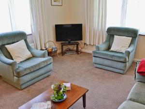 a living room with two chairs and a tv at Trewithen Farm Bungalow in St Merryn