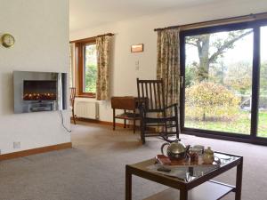 a living room with a fireplace and a table at Kingfisher Cottage in Pitlochry