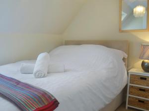 a white bed with two towels on top of it at Dolphin Cottage in Nairn