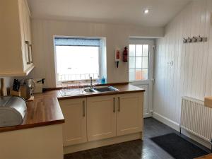uma cozinha com um lavatório e uma janela em Dolphin Cottage em Nairn