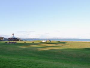 a view of a golf course with a gazebo and the ocean at Dolphin Cottage in Nairn