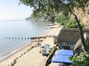 a beach with blue umbrellas and a house at 8 Old School Mews in Shanklin