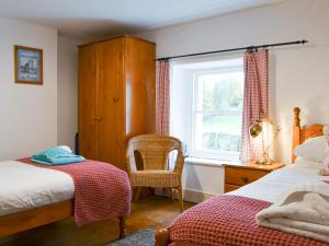 a bedroom with a bed and a window and a chair at Greenside Cottage in Caldbeck