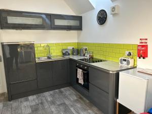 a kitchen with black cabinets and green tiles on the wall at 44 Inaclete Road in Stornoway
