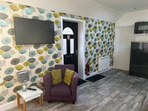 a living room with a purple chair and a flat screen tv at 44 Inaclete Road in Stornoway