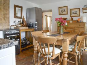 uma cozinha com uma mesa de madeira e cadeiras em Bryn Tirion em Llantrisant