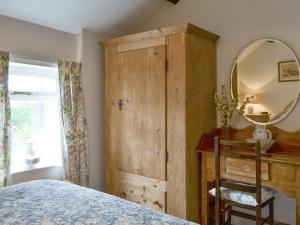 a bedroom with a wooden cabinet and a mirror at Bryn Tirion in Llantrisant