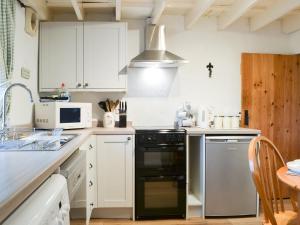 a kitchen with white cabinets and a black dishwasher at Greenside Cottage in Caldbeck