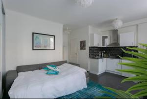 a bedroom with a white bed and a kitchen at Beau studio près de la TOUR EIFFEL / ROLAND GARROS in Boulogne-Billancourt